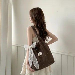 Vue détaillée du sac cabas en velours marron avec nœud en dentelle et broderie