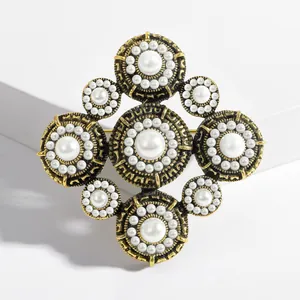 Detailed view of vintage Baroque pearl brooch with antique gold finish on white stand