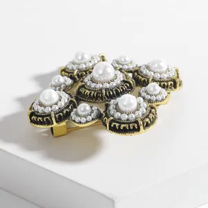 Detail of vintage Baroque pearl brooch with gold textured metal on white stone pedestal