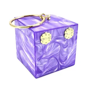 Detail of purple marble acrylic box clutch featuring golden metal ring handle