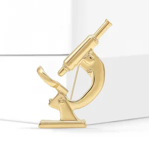 Macro shot of gold-plated microscope brooch on minimalist prop for lapel pin detail