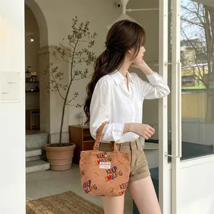 Detail of warm brown corduroy tote bag featuring Keep Smiling print and S-ZANKA label