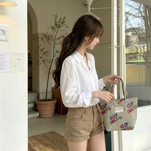 Corduroy tote bag featuring colorful Keep Smiling print and red woven label detail