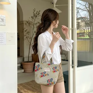 Detail of off-white corduroy tote bag with Keep Smiling print in a casual cafe setting