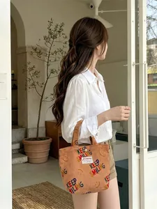 Brown corduroy tote bag with Keep Smiling print held by model in casual outfit