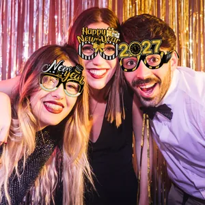 Three 2027 New Year party glasses in black and gold worn by models in festive setting