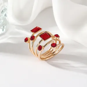 Detail of gold multi-layer wrap ring with large square and round red gemstones