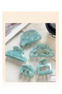 Detail view of five assorted mint green acrylic hair claws with elegant marble patterns