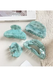 Set of four light blue marble pattern acrylic hair claws on a minimalist background