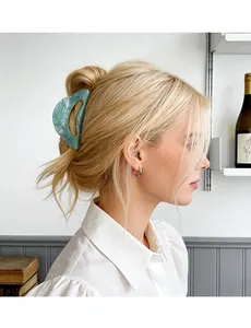 Detail of light green marble patterned claw clip in use on golden blonde hair