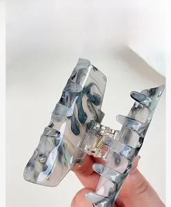 Detail of gray marble patterned resin hair claw clip with golden metal spring