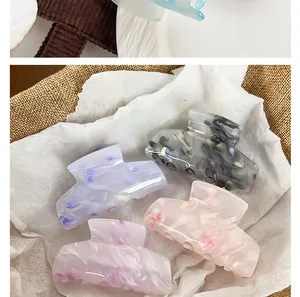 Close-up of four colorful acrylic shark hair claws featuring marble and floral patterns