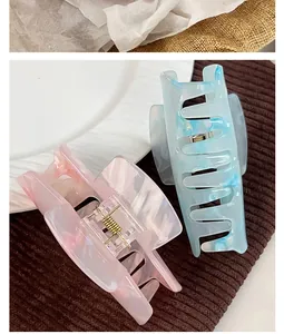 Detail view of large candy-colored acrylic hair claws with marble texture and metal spring