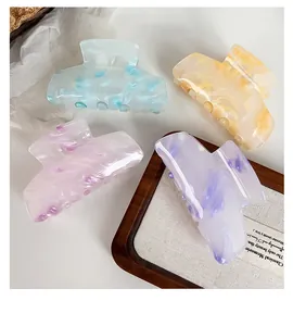 Close-up of four large marble-patterned acrylic hair claws in assorted pastel candy colors