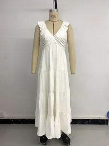 Detail of V-neck white tiered dress featuring ruffle shoulders and textured fabric