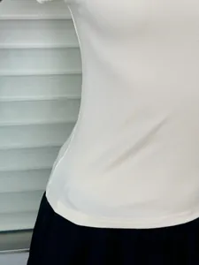 Close-up of white ribbed fabric texture and hem stitching on fitted short sleeve top