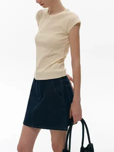 Detail of slim-fit cream raglan sleeve tee paired with dark blue denim A-line skirt