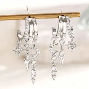Macro detail of asymmetric star and moon drop earrings with sparkling cubic zirconia