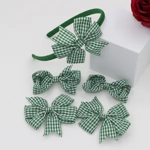 Detailed view of green gingham bow headband and hair clips on a white display block