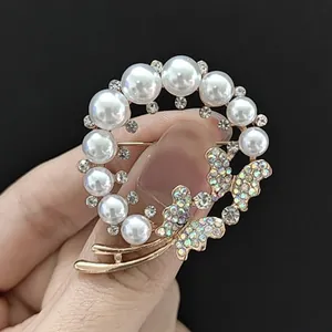Détail d'une broche couronne de perles avec papillon en cristal AB sur métal doré