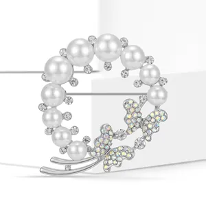 Détail d'une broche couronne de perles argentées avec papillon en cristal sur fond blanc