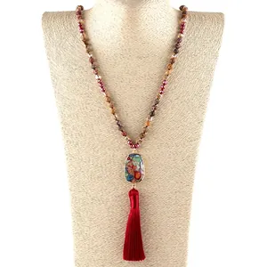 Detail of bohemian necklace with faceted stones and a long dark red silk tassel
