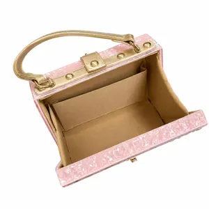 Pink acrylic evening clutch bag with gold handle and spacious fabric interior