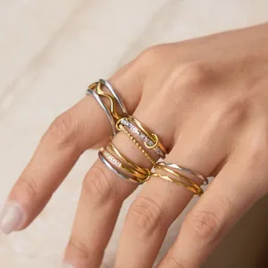 Detail of layered gold and silver rings with zircons on stone background texture