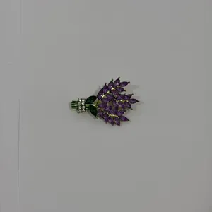 Macro detail of bouquet brooch with purple marquise crystals and green gemstone leaves