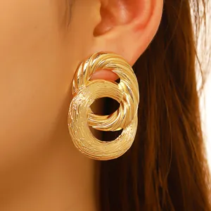 Close-up of triple-layered golden textured hoops showing detailed brushed metal finish