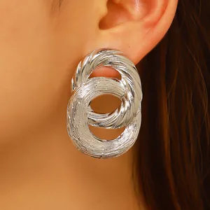 Macro shot of silver twisted double hoop earrings with textured finish on model