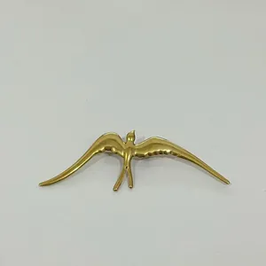 Détail d'une broche hirondelle dorée montrant les textures complexes des plumes d'ailes