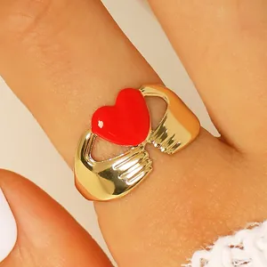 Primer plano de anillo bañado en oro con manos sujetando un corazón rojo