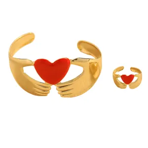 Detalle de set de joyas doradas con corazones de esmalte rojo y diseño ajustable