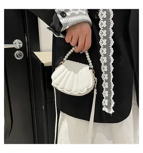 Photo portée du mini sac blanc en forme de coquillage avec anse en perles et matelassé