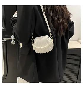 Détail du sac à main blanc en forme de coquillage avec texture et bandoulière perle