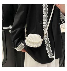 Vue détaillée d'un sac à main blanc en forme de coquille avec chaîne perlée et dorures