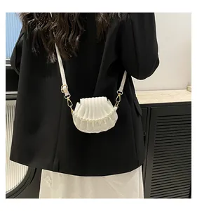Sac à bandoulière chic en forme de coquillage blanc avec perles sur un mannequin