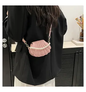 Détail du sac bandoulière rose en forme de coquillage avec perles porté par un mannequin