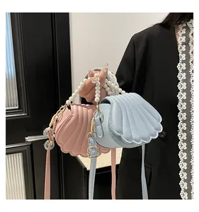 Détail de sacs à main en forme de coquillage avec poignées en perles et bandoulières