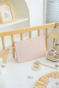 Detailed close-up of light pink quilted toiletry bag showing woven texture and strap