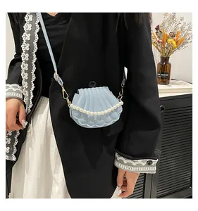 Gros plan d'un sac bandoulière coquillage bleu clair avec perles et crochets dorés