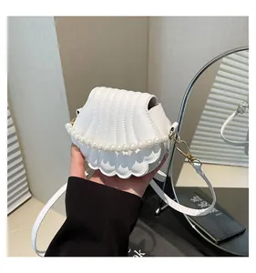 Détail du sac blanc en forme de coquillage avec chaîne en perles et bandoulière réglable