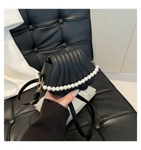 Détails du sac noir en forme de coquillage avec perles blanches et fermoirs dorés