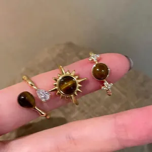 Three-piece gold sunflower rings set with tiger eye stones and sparkling diamonds on hand