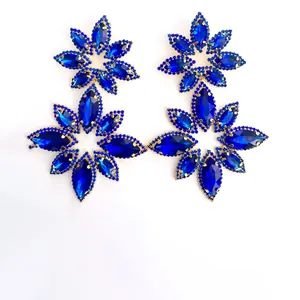 Detailed macro of oversized flower-shaped stud earrings with deep blue marquise crystals