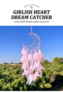 Close-up of pink crescent moon dreamcatcher with feathers against a blue sky