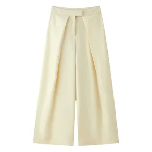 Detail view of high-waist cream wide-leg trousers featuring deep front pleats