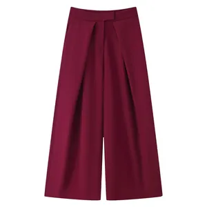 Detail view of the elegant pleated burgundy wide-leg trousers with flat waistband