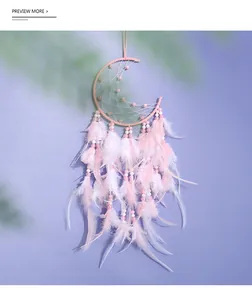 Detail of pink moon-shaped dream catcher with delicate feathers and soft beads